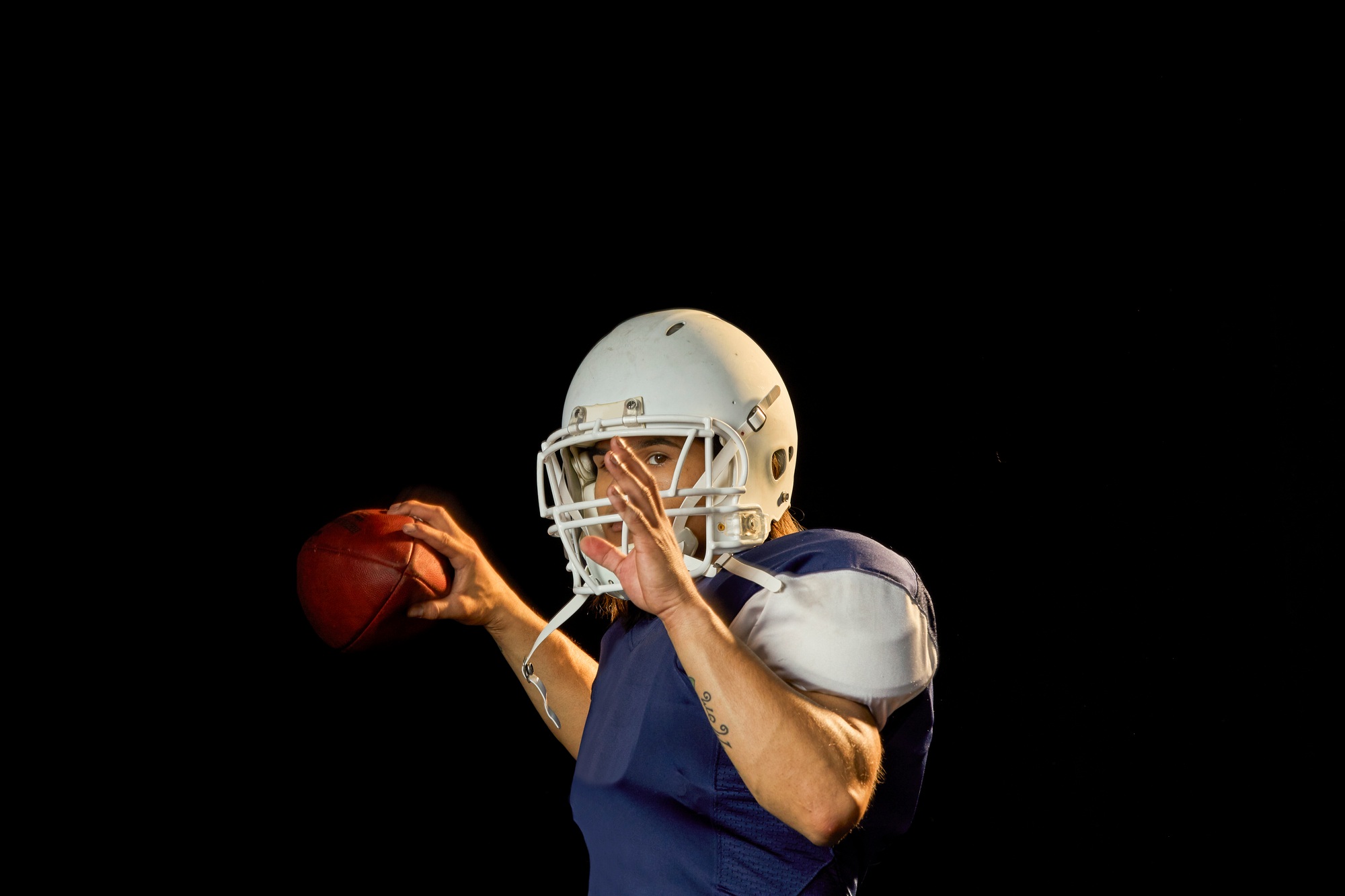 Portrait of quarterback with football, black background